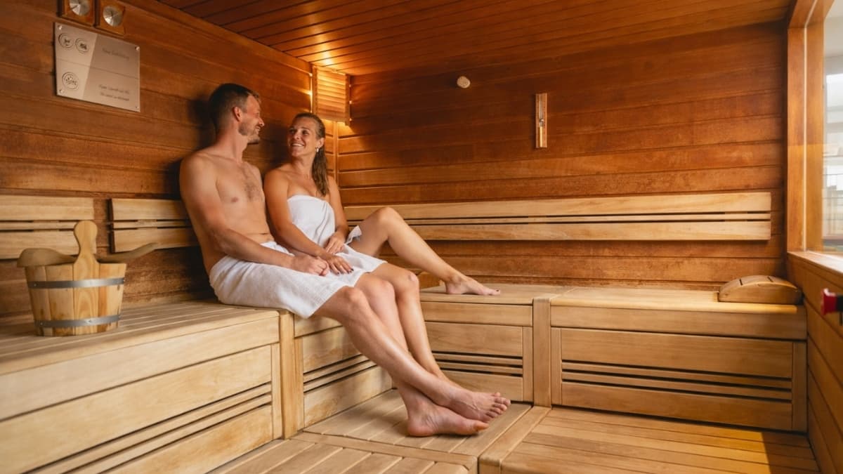 Couple relaxing inside a wooden Finnish sauna at a EuroParcs wellness retreat with private sauna experience