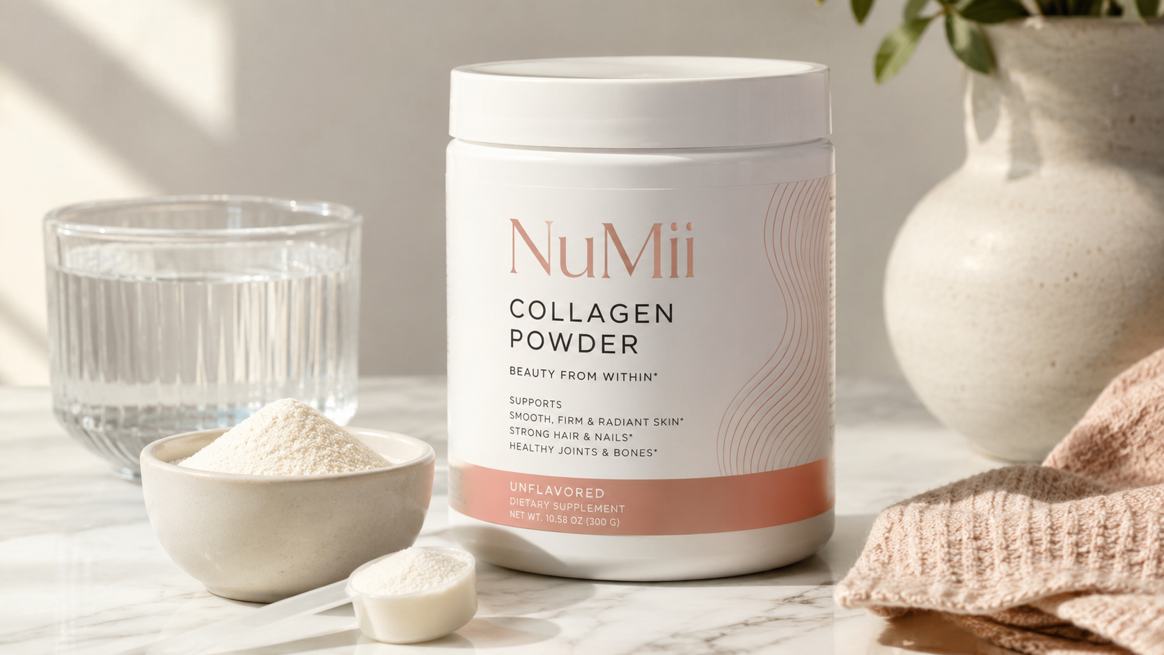 NuMii Collagen Powder unflavored dietary supplement in a white container with collagen powder, scoop, and glass of water on a marble countertop for skin, hair, nail, and joint support.