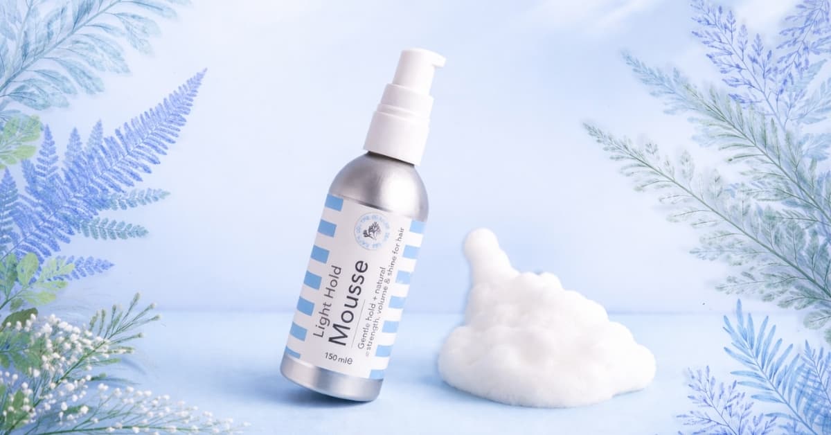 Light hold hair mousse bottle next to airy foam, showing lightweight styling product for soft volume and natural hair texture